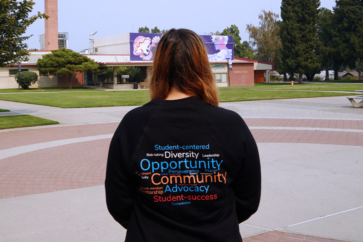 Woman showing back of sweatshirt that has writing on it. Located by WVC fountain.