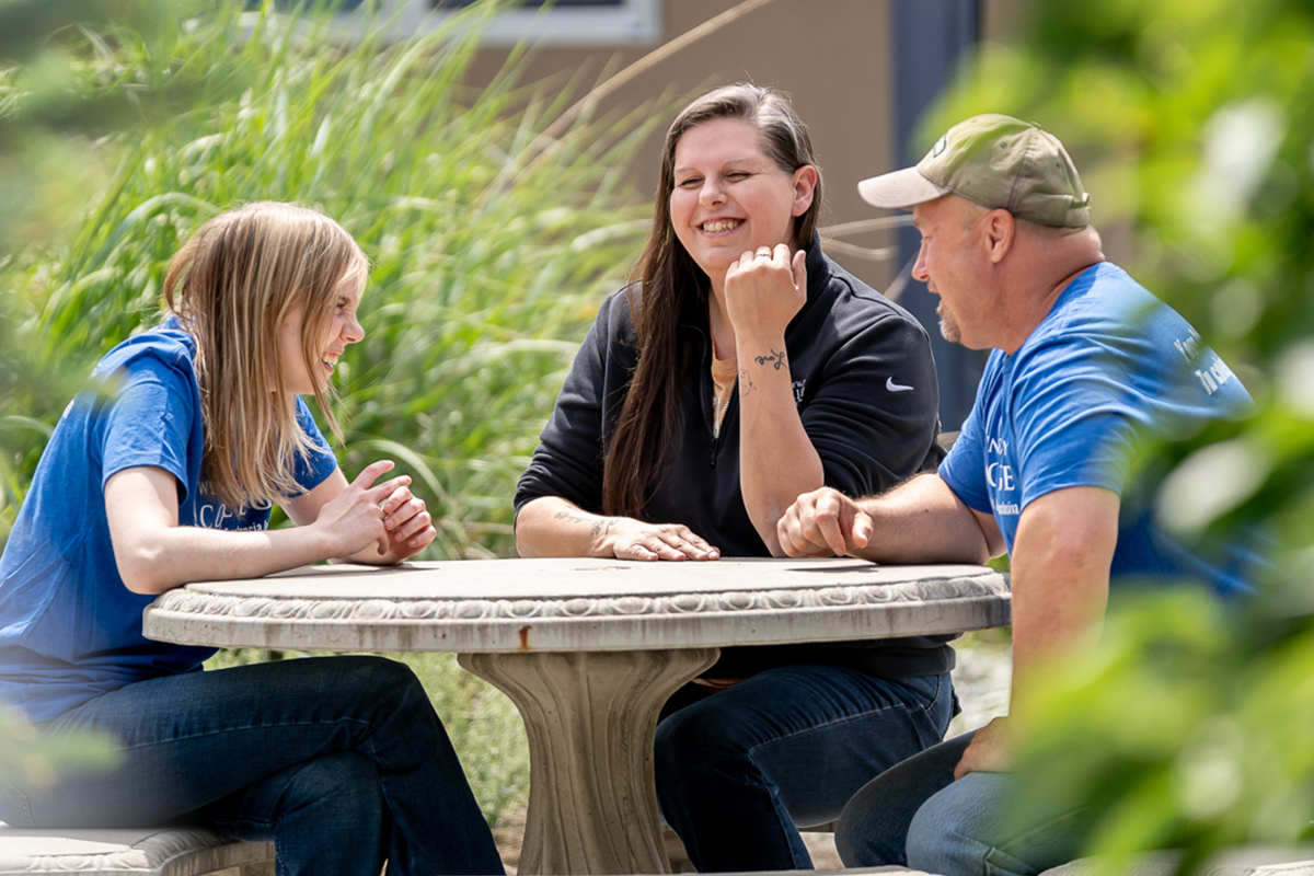 Three students outside sitting at a table.