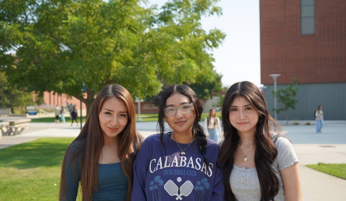 Three students standing outside Mish ee twie by fountain
