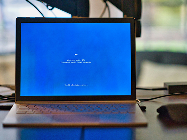 A blue laptop screen with a message about updates occurring.