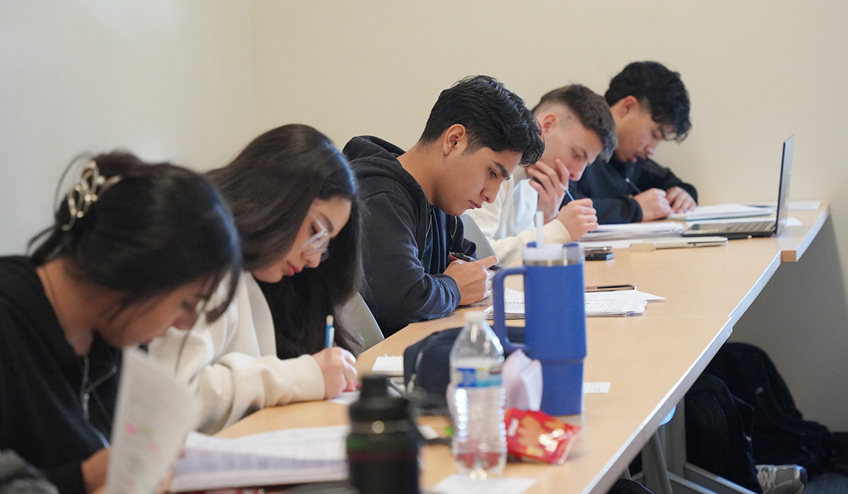 A group of students sit at a table to complete an accounting sheet.