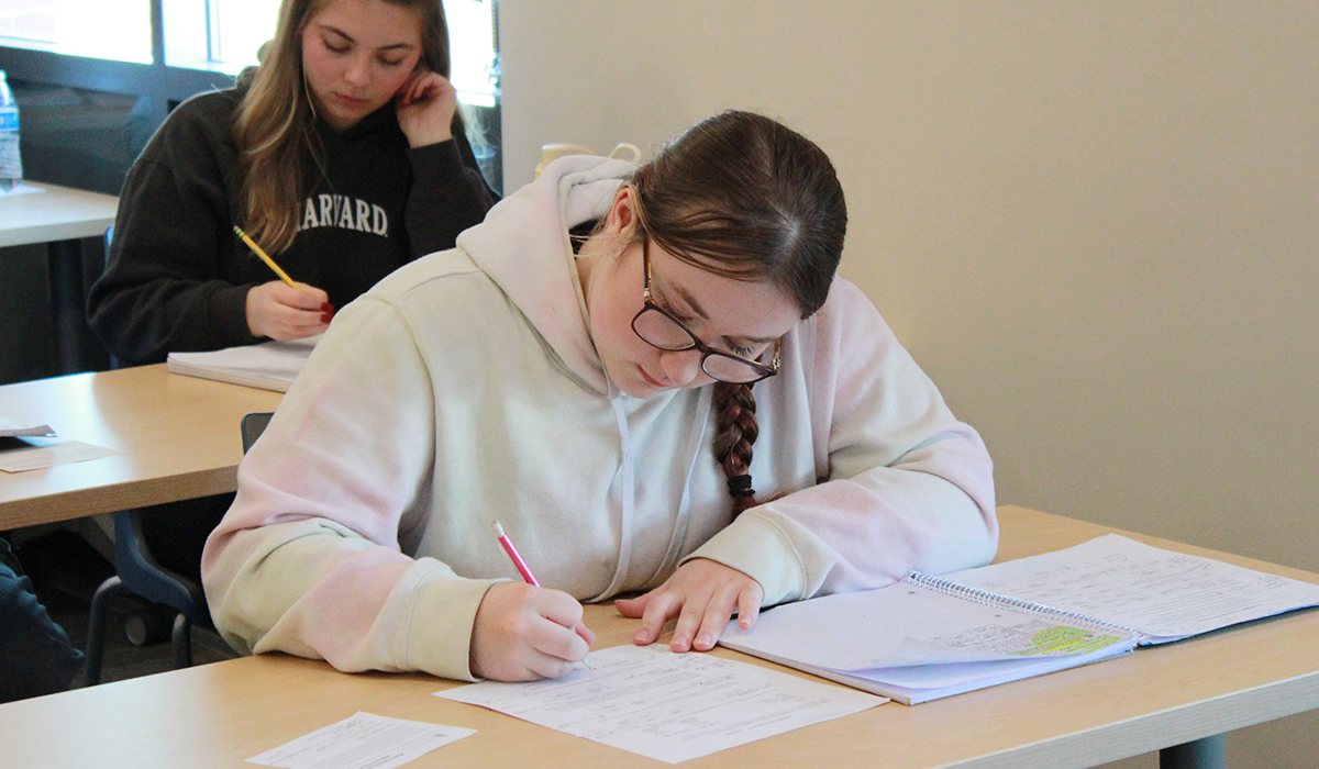 A student writes on an accounting worksheet.