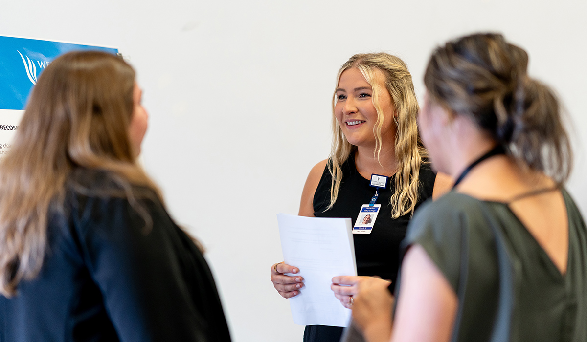 A WVC Omak LPN graduate talks with two visitors about her poster project.