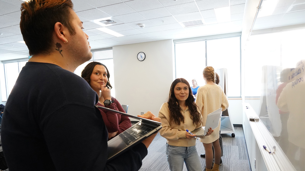 Students talk with a nursing instructor in a classroom.