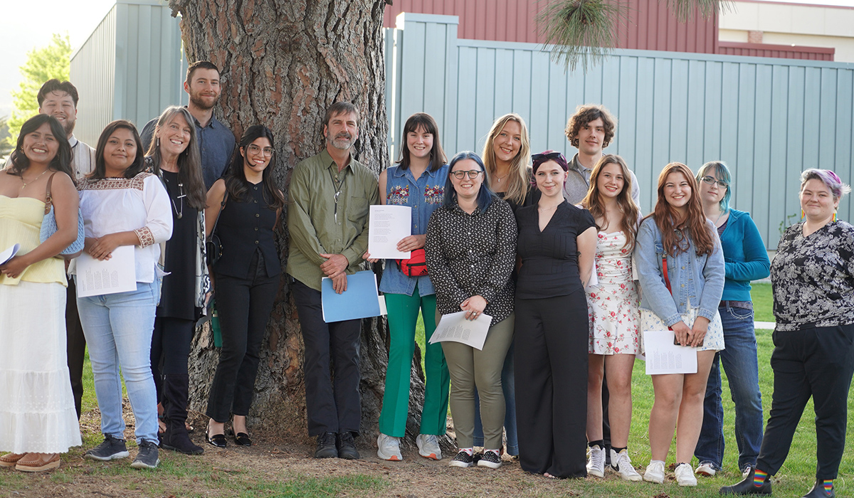 A group of creative writing students stand with two English professors