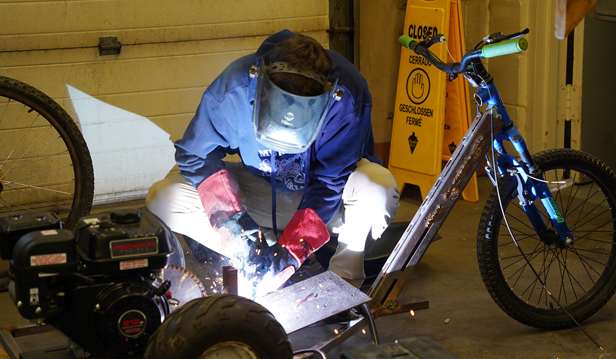 A welding student completes a weld on a motorcycle.