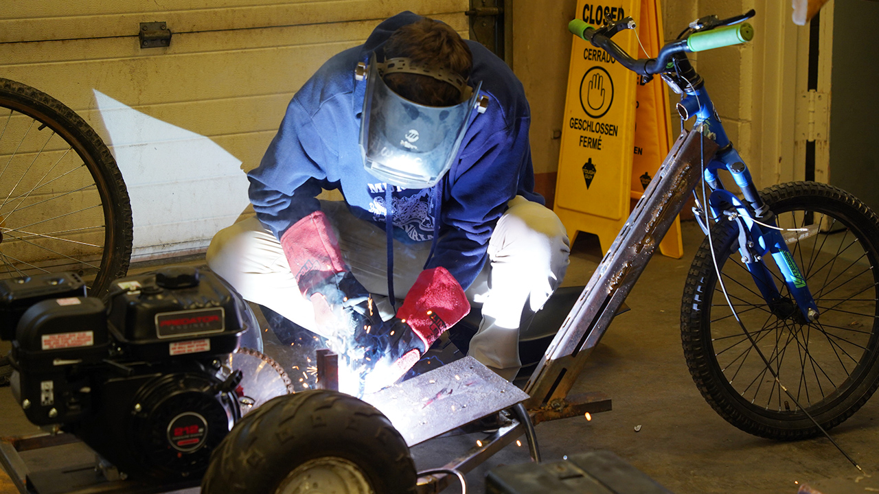A student completes a weld on a motorized bike.