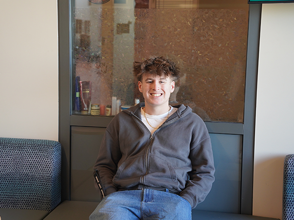 WVC student Ethan Kamphaus sits on a bench in front of an office window.